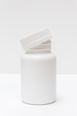 white plastic bottle with cap for pills on a light background