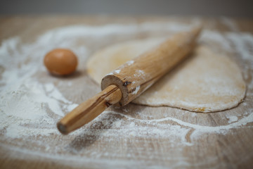 The girl prepares the dough for homemade noodles. On the table there is everything you need.