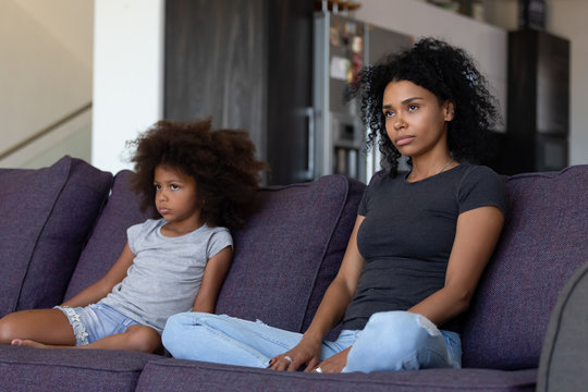 Unhappy sulky african child girl and annoyed mother sitting on sofa not talking after fight, stubborn mixed race kid daughter and mom ignore each other upset by quarrel, black family conflict concept