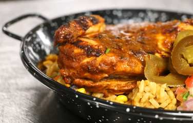 spice roasted whole baby chicken with flavored rice in a serving dish
