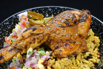 spice roasted whole baby chicken with flavored rice in a serving dish