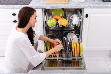 Woman Arranging Plates In Dishwasher