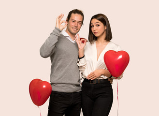 Fototapeta na wymiar Couple in valentine day showing an ok sign with fingers over isolated background