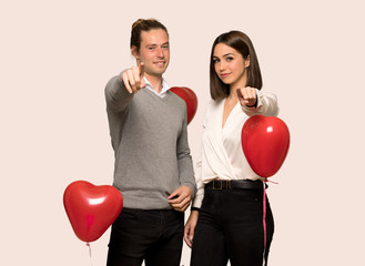 Fototapeta na wymiar Couple in valentine day points finger at you with a confident expression over isolated background