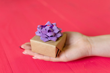 female hands give present on wooden red background