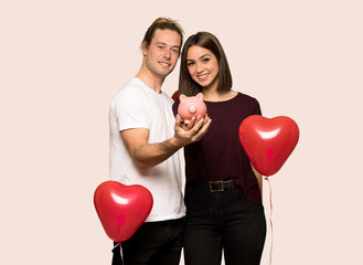 Fototapeta na wymiar Couple in valentine day holding a piggybank over isolated background