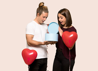 Fototapeta na wymiar Couple in valentine day holding gift box in hands over isolated background