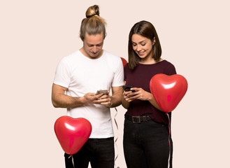 Couple in valentine day sending a message with the mobile over isolated background