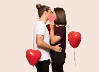 Fototapeta na wymiar Couple in valentine day holding a heart symbol and kissing over isolated background