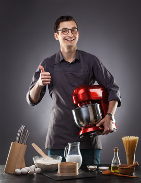 Man Holding Red Food Processor On A Gray Background