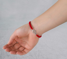 red thread with a cross on the hand of a girl