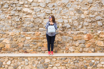 Young funny emotional woman with handbag posing on stone urban background
