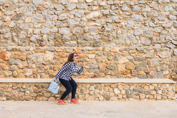 Emotions and gestures - Portrait of funny woman running away on stone wall background