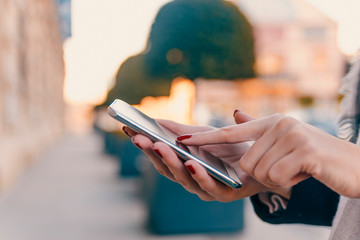 Girl pointing finger on screen smartphone on background illumination bokeh color light in night atmospheric city, using in hands texting mobile phone. Using cellphone