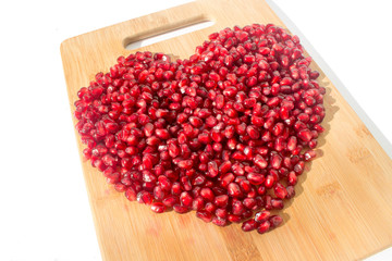 Red pomegranate fruit. Ripe vegetarian food. Heart of sweet juicy fresh organic seed wood background. Healthy raw closeup tropical half piece with juice. Love. Saint Valentine day.