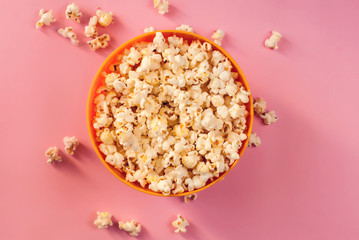 A bowl with popcorn on pink background.