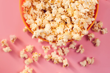A bowl with popcorn on pink background.