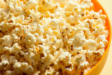 An orange bowl with popcorn isolated on yellow background