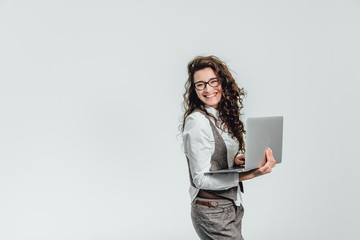 Naklejka premium BBeautiful young girl smiles. Works on a laptop in glasses and a white shirt