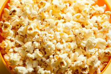 An orange bowl with popcorn isolated on yellow background