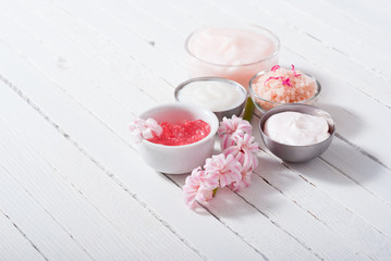 beauty and cosmetic creams with pink flowers on white wood