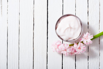 beauty and cosmetic creams with pink flowers on white wood