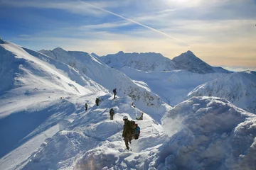Foto auf Acrylglas Bergsteigen Gebundene Kletterer klettern auf den Berg mit Schneefeld, das mit einem Seil mit Eispickel und Helmen gefesselt ist