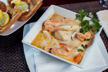 Seafood cream soup with toasts in white plate on the table. Food and restaurant concept