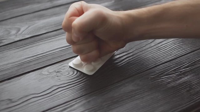 Saying no to drugs or refuse to use medicine. Human hand crushing white pills with fist. Anti doping or against unethical pharmaceutical business. Stop tablets