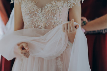 Morning preparations. Woman putting on dress. Gorgeous, blonde bride in pink luxury dress