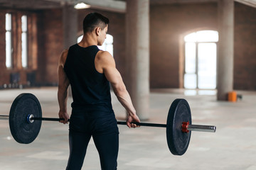 well-built athlete holding weight, copy space. guy doing weight training exercises indoors