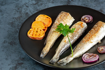 Fried hake served with sweet potatoes and red onion.