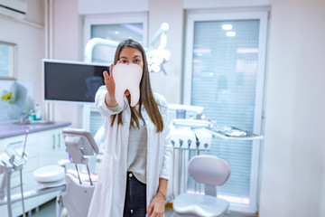 Young female dentist holding tooth model