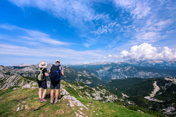 Rear view of man and woman in middle age with backpack hiking in beautiful mountain panorama, Slovenia