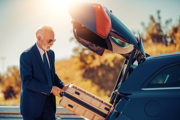 Senior businessman traveling to work wit car.