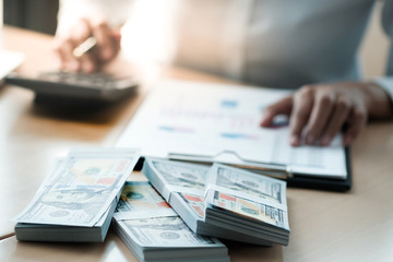 Businesswoman analyzing investment charts and pressing calculator buttons over documents. Accounting Concept.