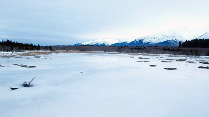 Drone flying over frozen marsh in Alaska during the evening