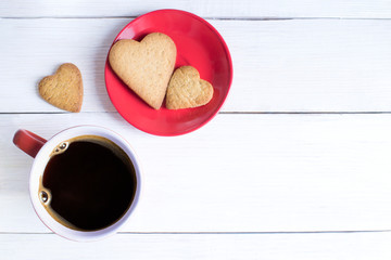 Heart-shaped gingerbread and cup of coffee on a white wooden background, with free space for your text. Top view