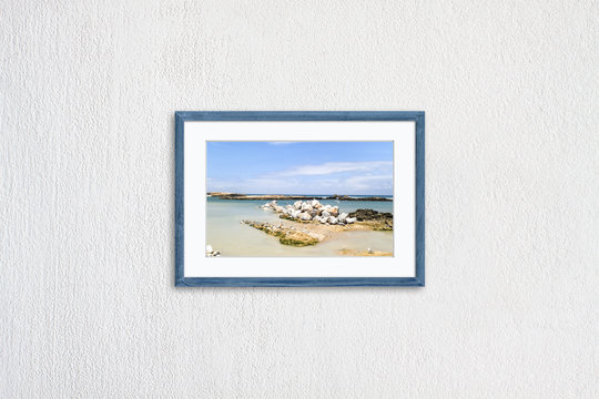 Frame mock up with oceanview and seagulls picture, grey blue realistic wooden framework isolated on white plastered wall