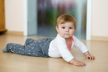 Little cute baby girl learning to crawl. Healthy child crawling in kids room. Smiling happy healthy...