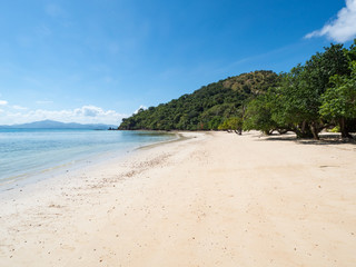 Tropical beach with palm trees, blue sky, turquoise water and white sand. Paradise. Philippines, Palawan, Banana island. Wide angle, horizontal. November, 2018