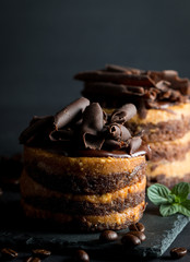 Chocolate cakes on black slatter board with mint, coffee beans on dark background, closeup photo. Fresh, tasty dessert food concept. 