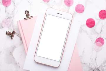 Mobile phone with a pink notebook with pink decorations on a marble background