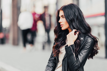 Fototapeta premium Young pretty latin woman walking near shops in city centre