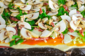 Process of making pizza. Italian pepperoni pizza with mushrooms, ruccola, tomatoes, mozzarella, garlic and sauce