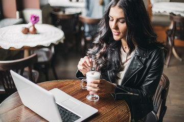 Young pretty spanish woman in cafe in city centre with tablet laptop