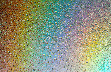 Drops of water on the glass, with the reflection of the rainbow.