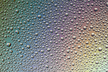 Drops of water on the glass, with the reflection of the rainbow.