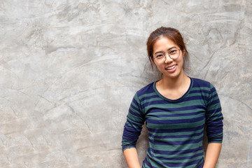 Young pretty asian woman with glasses smiling in grey concrete wall background,