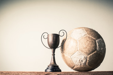 still life photography : old football and vintage trophy on old wood table in championship concept